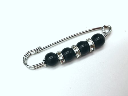 Anstecknadel, silberfarben, schwarzes Acryl, &Oslash; 6 mm und dazwischen drei Ringe mit Strasssteinen.