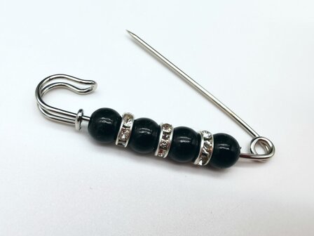 Anstecknadel, silberfarben, schwarzes Acryl, &Oslash; 6 mm und dazwischen drei Ringe mit Strasssteinen.