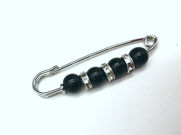 Anstecknadel, silberfarben, schwarzes Acryl, Ø 6 mm und dazwischen drei Ringe mit Strasssteinen.